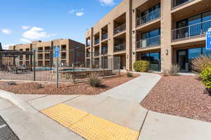 Front of building and surrounding community featuring fenced pool