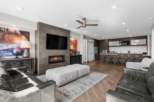 Living room with a tiled fireplace, parquet flooring, a ceiling fan, and recessed lighting