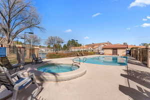 Community pool with an in ground hot tub, a patio, and fence