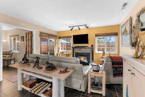 Tiled living room with a glass covered fireplace and visible vents