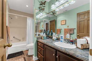 Bathroom featuring visible vents, toilet, shower / tub combo with curtain, tile patterned flooring, and vanity