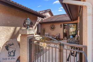 Entrance to property with a tile roof, a gate, and stucco siding