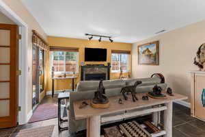 Dining area featuring dark tile patterned flooring, a fireplace, visible vents, and a healthy amount of sunlight