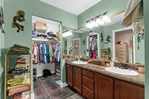 Bathroom featuring double vanity, tile patterned flooring, a walk in closet, and a sink