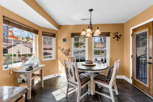 Dining area featuring a chandelier, dark tile patterned flooring, visible vents, and baseboards