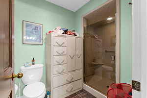 Bathroom featuring toilet, a stall shower, and tile patterned floors