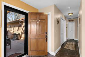 Foyer with dark tile patterned floors and baseboards