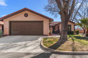 View of front of property with an attached garage, fence, a tile roof, driveway, and stucco siding