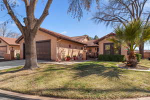 View of front of house featuring a gate, fence, a front lawn, and stucco siding