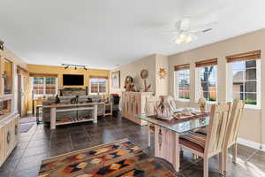 Dining area with baseboards, ceiling fan, rail lighting, a textured ceiling, and dark tile patterned floors