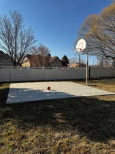 View of basketball court featuring basketball court, a yard, and fence