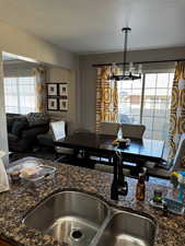 Interior space featuring a textured ceiling, dark stone countertops, a sink, and an inviting chandelier