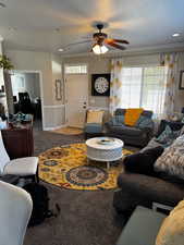 Living area with ceiling fan, a textured ceiling, carpet flooring, baseboards, and crown molding