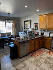 Kitchen featuring a sink, a peninsula, brown cabinetry, and dishwasher