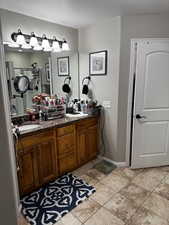 Full bath with double vanity, a sink, walk in shower, baseboards, and tile patterned floors