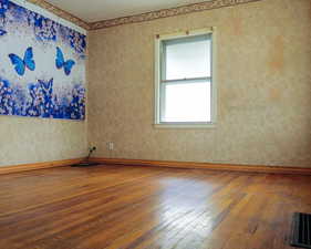 Spare room with hardwood / wood-style flooring, baseboards, visible vents, and a textured ceiling