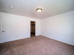 Unfurnished bedroom with carpet floors, a spacious closet, a closet, and baseboards