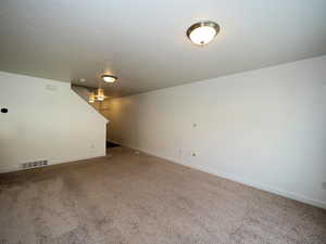 Interior space with a textured ceiling, carpet, visible vents, and baseboards