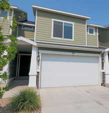 View of front of home featuring a garage, stone siding, and concrete driveway