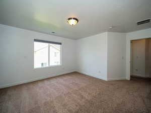 Carpeted empty room with visible vents and baseboards