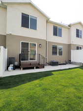 Back of property with a yard, a patio area, fence, and stucco siding