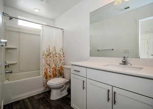 Bathroom with toilet, wood finished floors, visible vents, vanity, and shower / bath combo