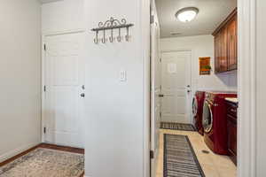 Clothes washing area with cabinet space, baseboards, visible vents, a textured ceiling, and washer and dryer