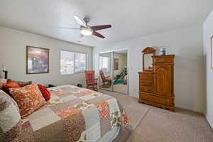 Bedroom with a textured ceiling, ceiling fan, light colored carpet, baseboards, and a closet