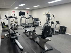 Exercise room with a paneled ceiling and baseboards