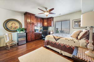 Bedroom featuring visible vents, a ceiling fan, built in study area, dark wood-type flooring, and a textured ceiling