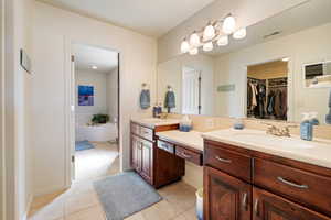 Bathroom with tile patterned flooring, visible vents, vanity, and a spacious closet