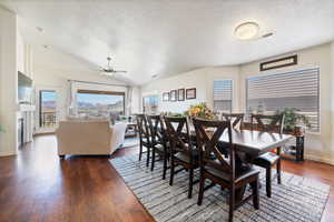 Dining space with lofted ceiling, visible vents, dark wood-type flooring, and a wealth of natural light