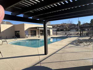 Community pool featuring a patio, fence, and a pergola