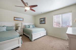 Bedroom with light carpet, baseboards, visible vents, and a ceiling fan