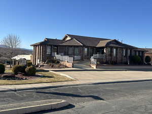 View of front facade featuring a tile roof, covered porch, brick siding, and concrete driveway