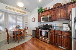 Kitchen featuring baseboards, visible vents, dark wood-style flooring, stainless steel appliances, and a textured ceiling