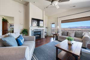 Living area with ceiling fan, a premium fireplace, wood finished floors, visible vents, and vaulted ceiling