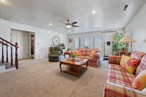 Living area featuring baseboards, light colored carpet, ceiling fan, stairway, and recessed lighting