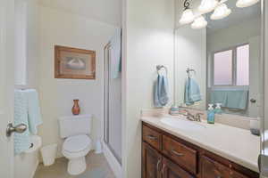 Full bath featuring toilet, vanity, baseboards, tile patterned floors, and a shower with door