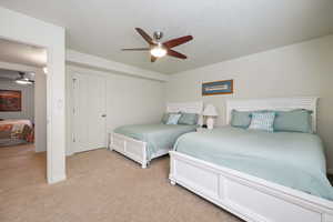 Bedroom featuring a ceiling fan, light carpet, a textured ceiling, and baseboards