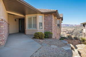 Entrance to property with a tile roof, brick siding, a mountain view, and stucco siding