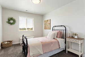 Bedroom featuring baseboards, visible vents, and dark carpet