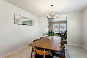 Dining room with light tile patterned floors, baseboards, and an inviting chandelier