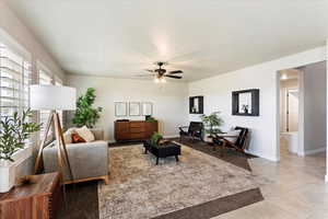 Living area with light tile patterned floors, baseboards, and a ceiling fan