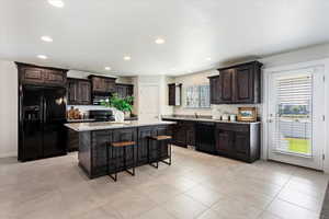 Kitchen with a center island, recessed lighting, black appliances, dark brown cabinets, and a kitchen breakfast bar