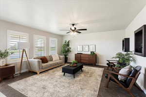 Carpeted living room with ceiling fan and baseboards