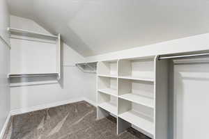 Spacious closet with carpet flooring and vaulted ceiling