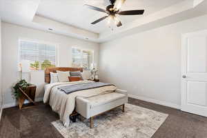 Bedroom with carpet flooring, a raised ceiling, visible vents, and baseboards