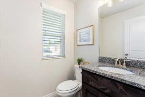 Bathroom featuring toilet, baseboards, and vanity