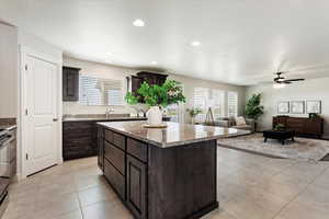 Kitchen with a center island, light tile patterned floors, recessed lighting, a sink, and dark brown cabinets